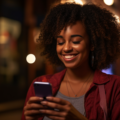 African American woman in her 20's holding a phone smiling | Madison Ave Magazine