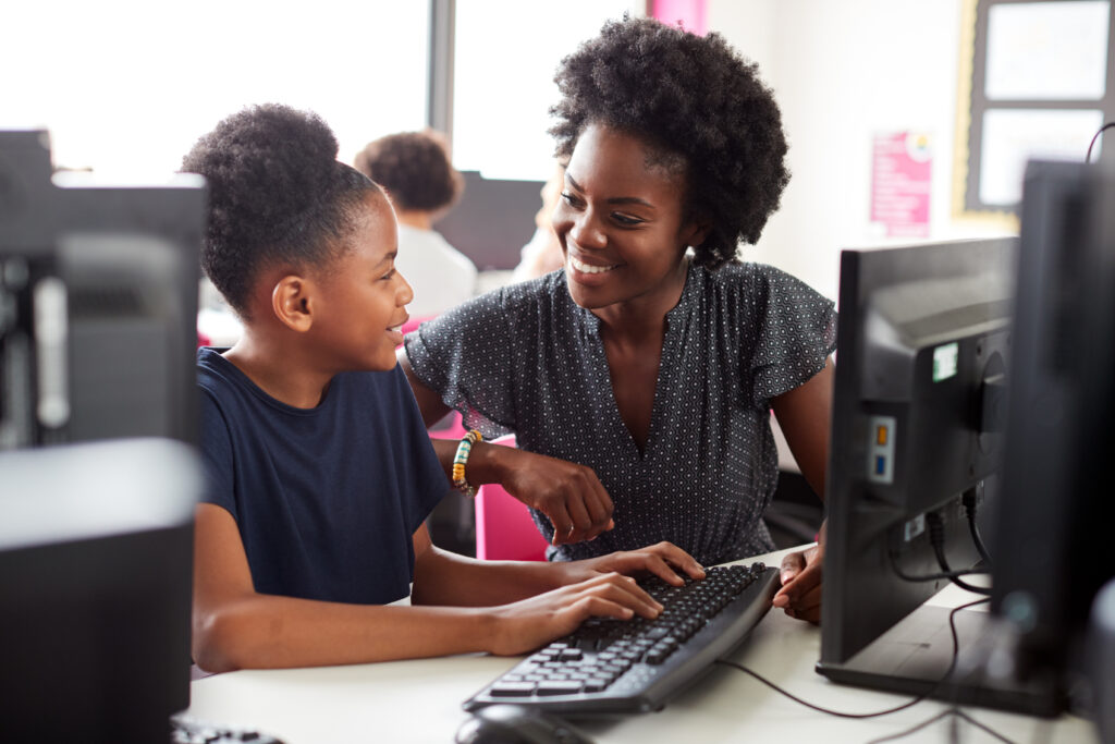 A Black teacher shows a young black girl how to code - Black Women In Tech, Madison Ave Magazine