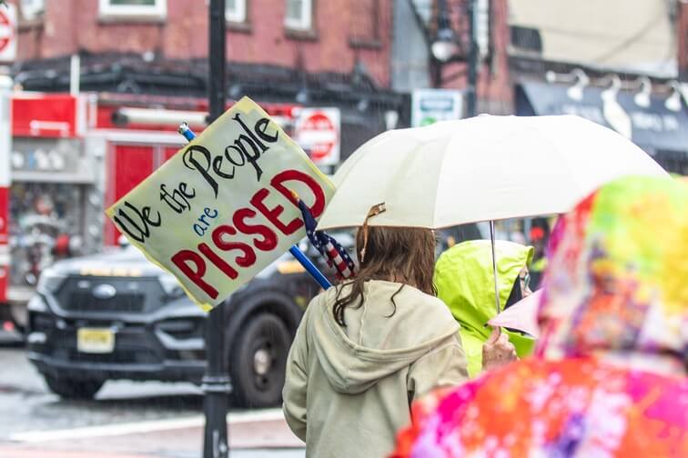 Protestor holds up sign that says we the people are pissed